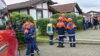Jugendfeuerwehrleute neben ausgelegten Schläuchen