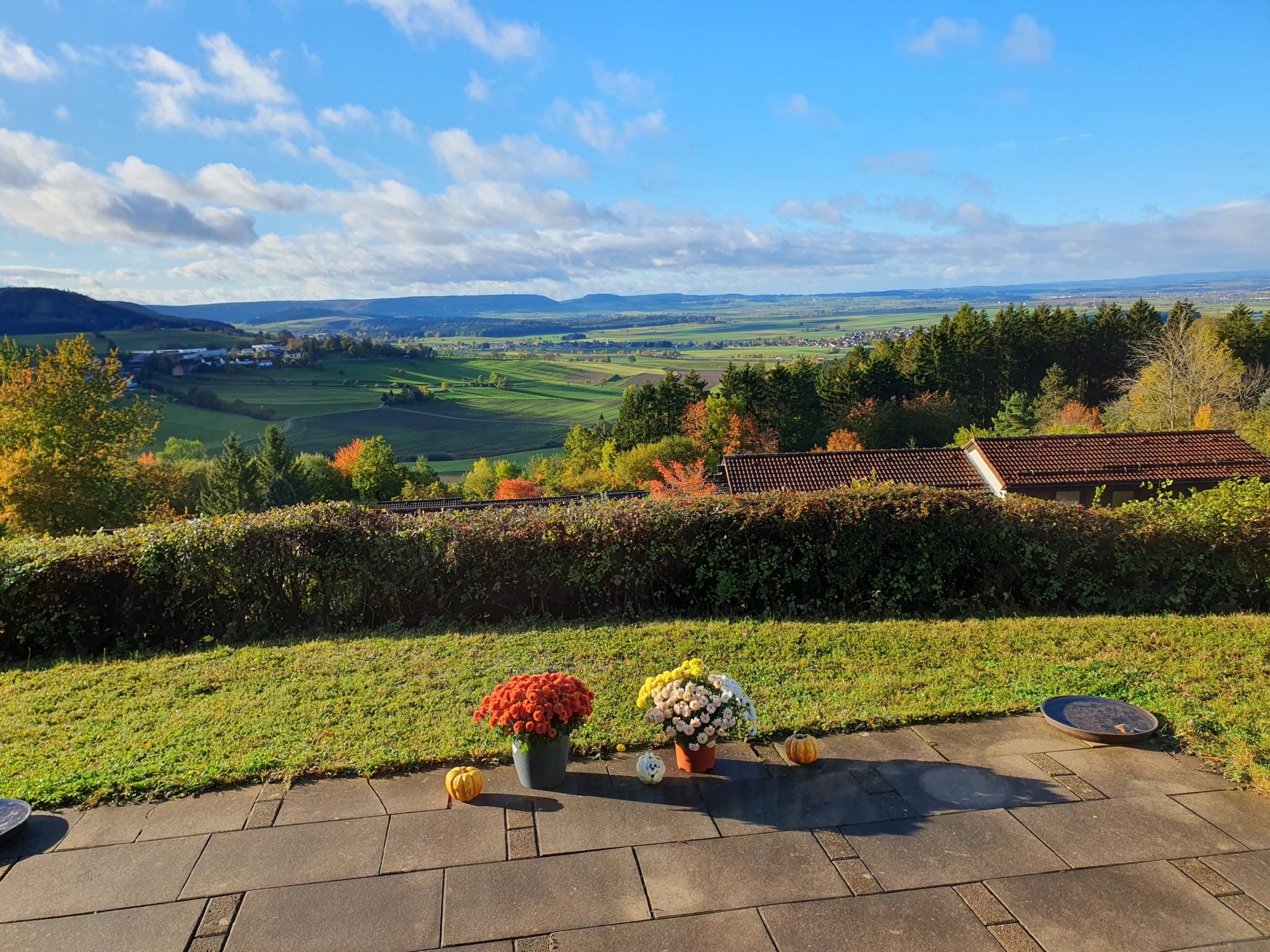 Blick vom Feriendorf über die Baar-Landschaft, Wiesen und Felder, leicht bewölkter Himmel